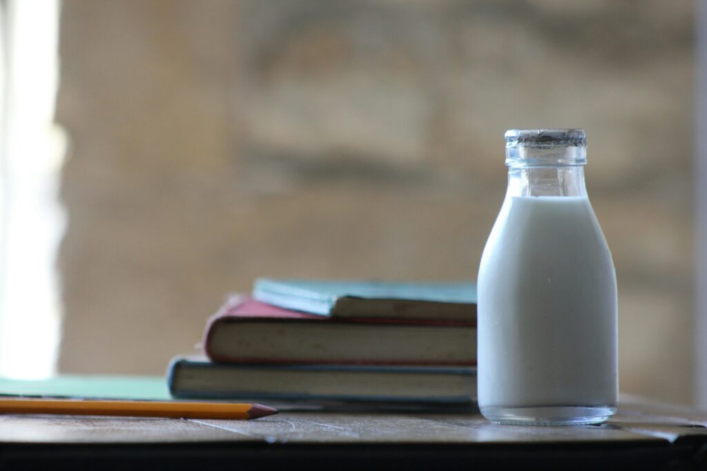 Milk in glass bottle aside books.