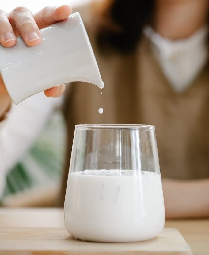 Unrecognizable Woman Pouring Milk from Jug to Glass