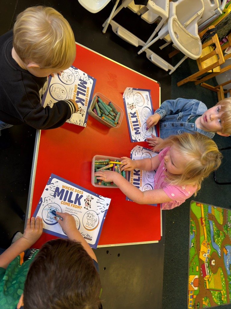 Children colouring 'Where does milk come from?' activity sheets with crayons