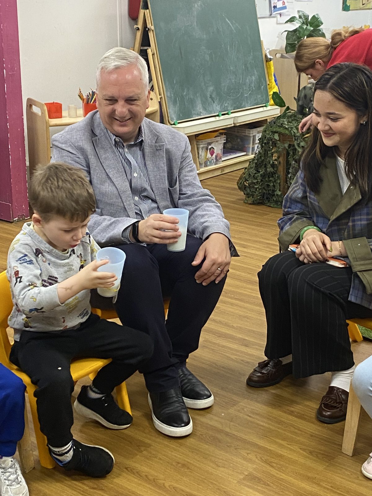 Daniel Francis MP sharing a cup of milk with a young child at nursery